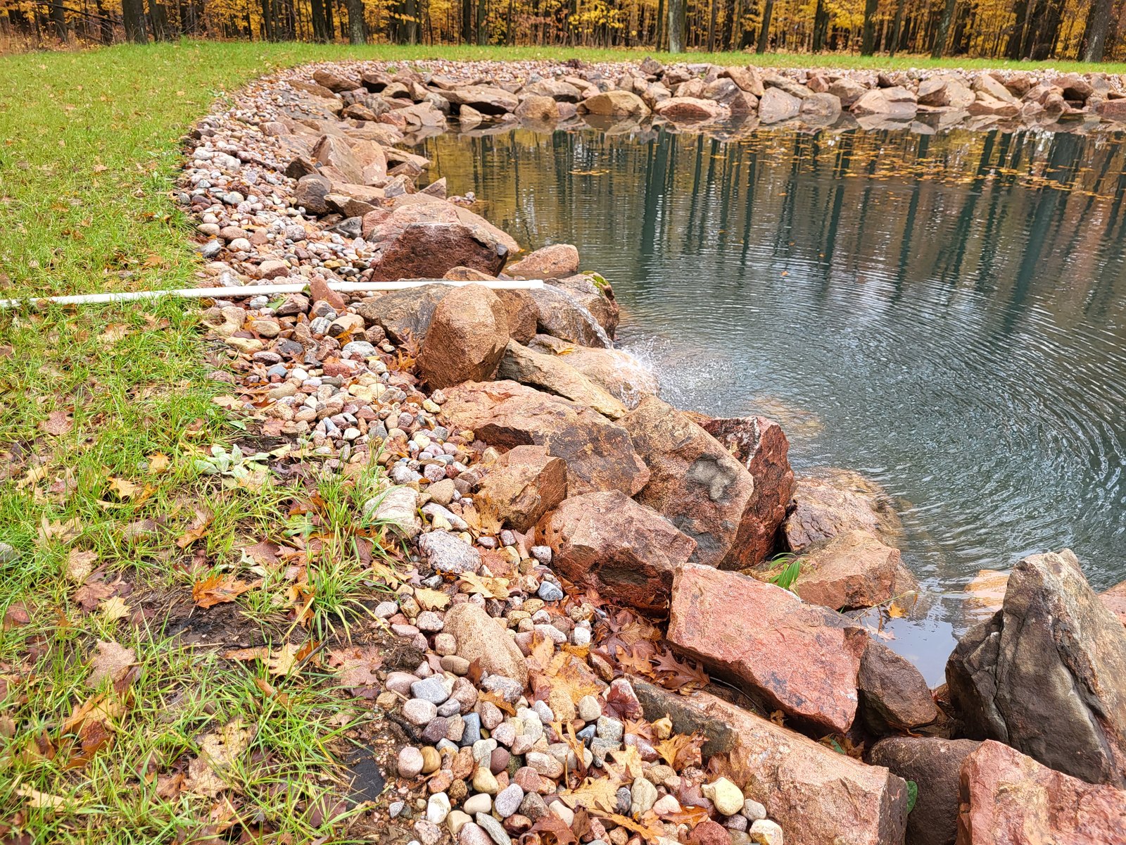 Custom man-made pond with a boulder edge and waterfall